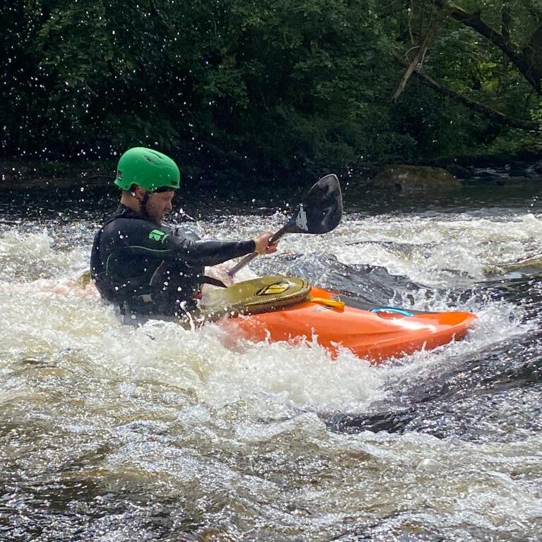 Person kayaking in turbulent river water.